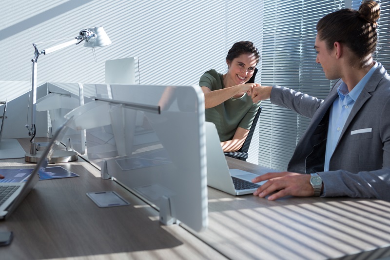 Happy executives celebrating success with fist bump in the office